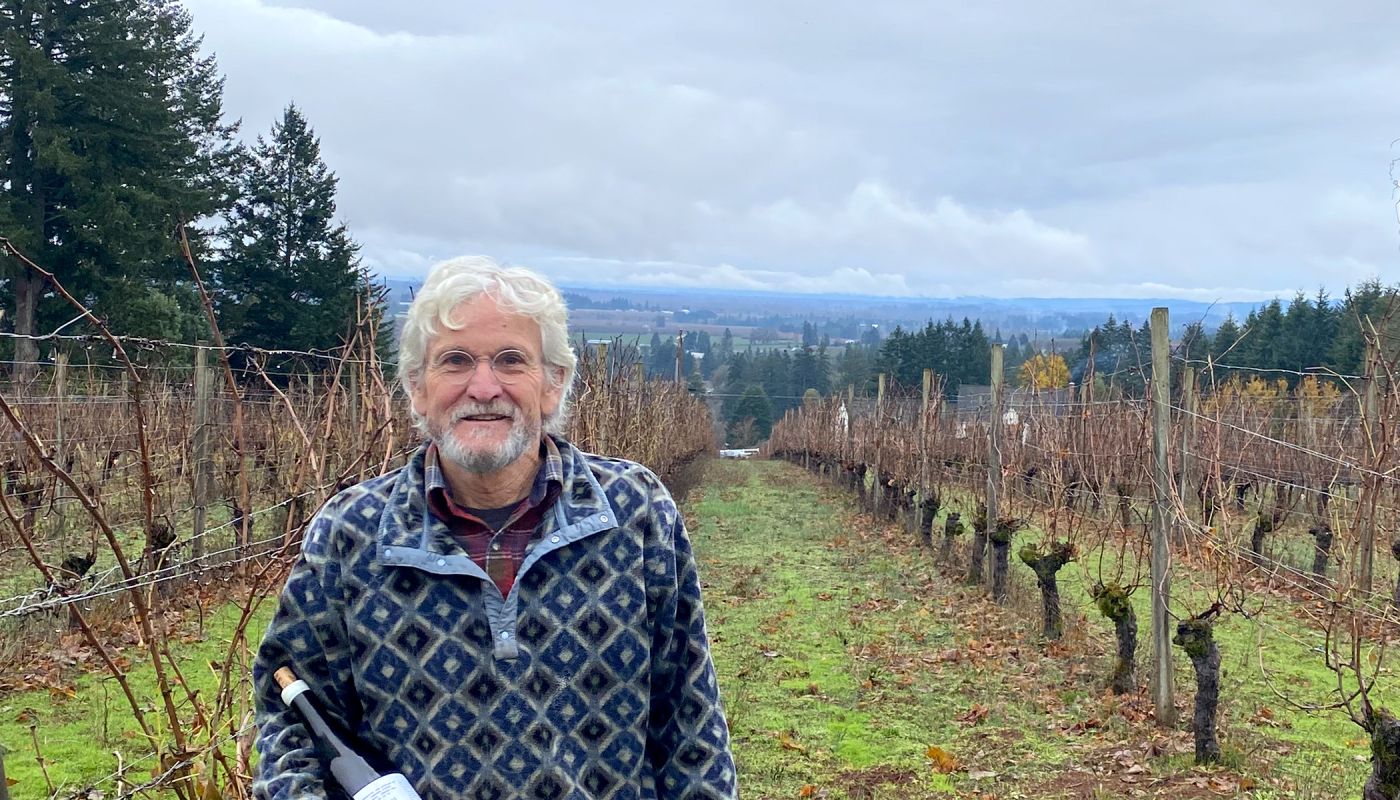 John Paul Cameron of of Cameron Winery in Oregon’s Willamette Valley stands in his vineyard holding a bottle of his wine.