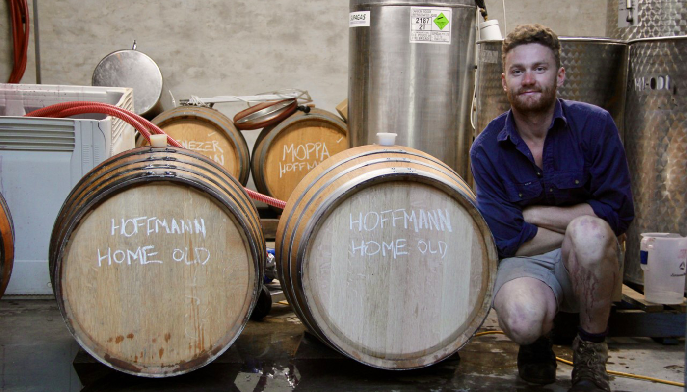 Winemaker Callum Powell kneeling next to his wine barrels