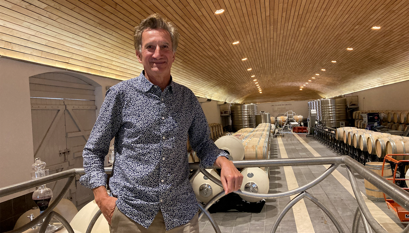 Jacques Lurton standing in an untucked blue-and-white flowered button-down shirt in his cellar.