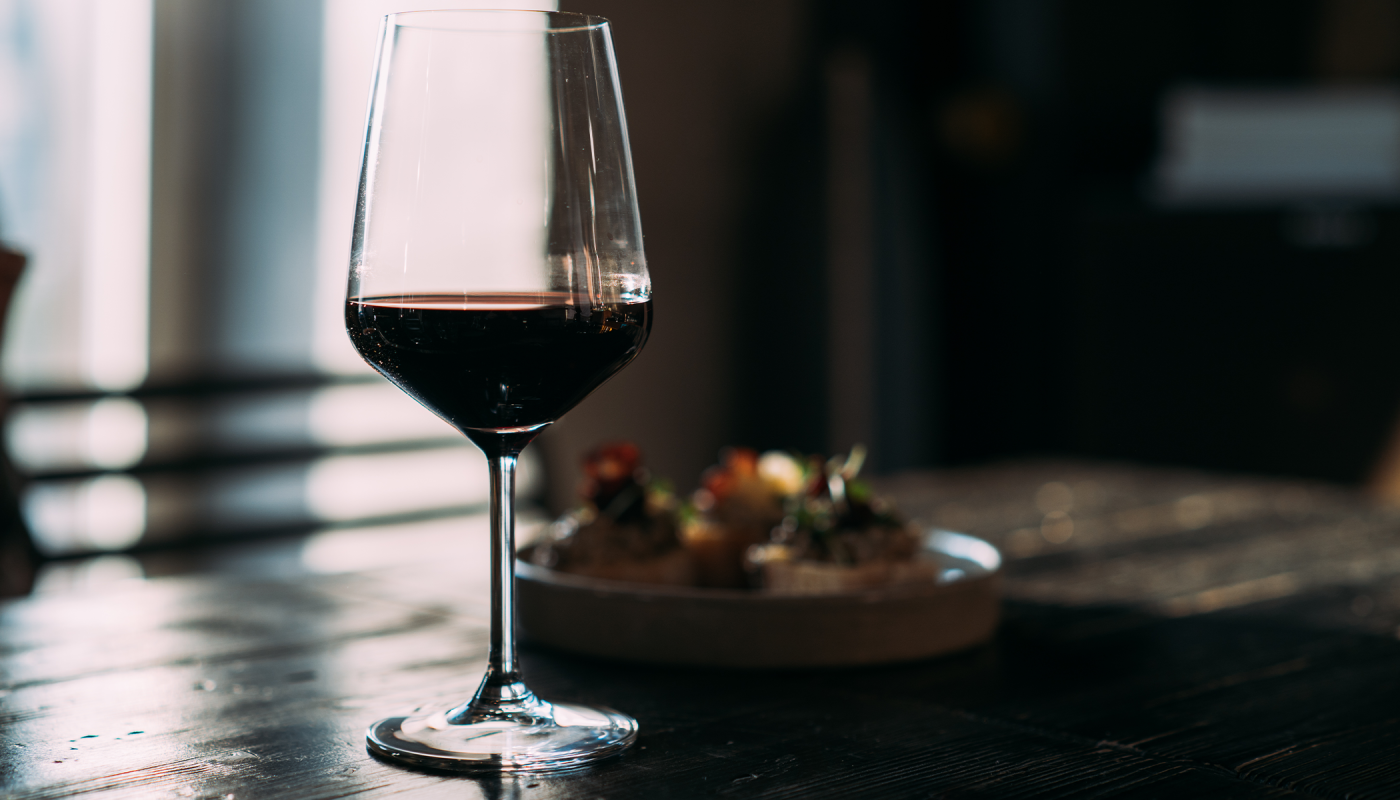 Glass with red wine on the wooden table in the bar; credit Dulin