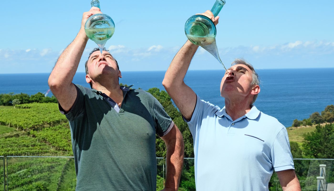 Ignacio Ameztoi and his father drink Txakoli out of porron.