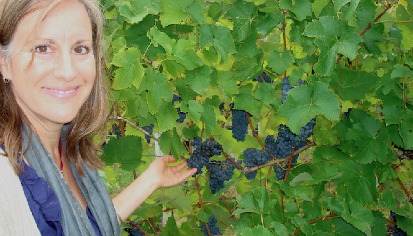Deborah Hansen in vineyard with dark purple grapes