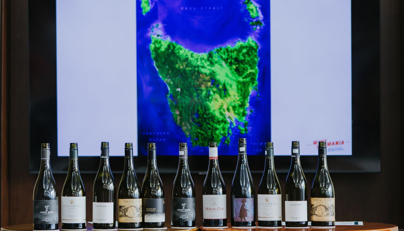 Bottles of Tasmanian wine standing in front of a screen showing a map of Tasmania