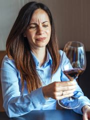 woman inspecting a glass of wine looking disappointed