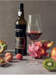 A bottle and glass of sweet Madeira surrounded by tropical fruits