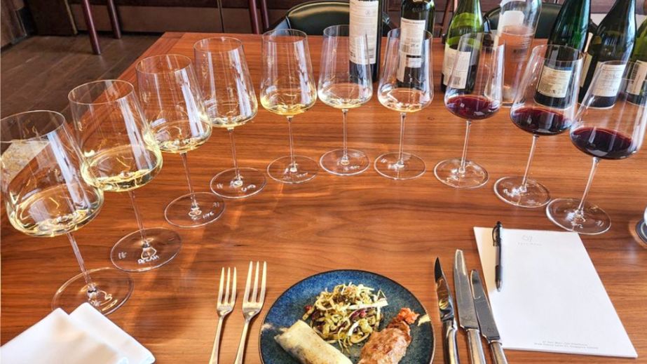 A plate of food surrounded by ten wine glasses