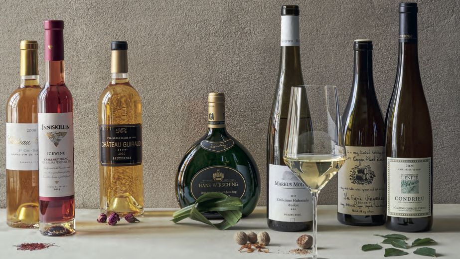 Still-life photograph of bottles of wine and various herbs and spices