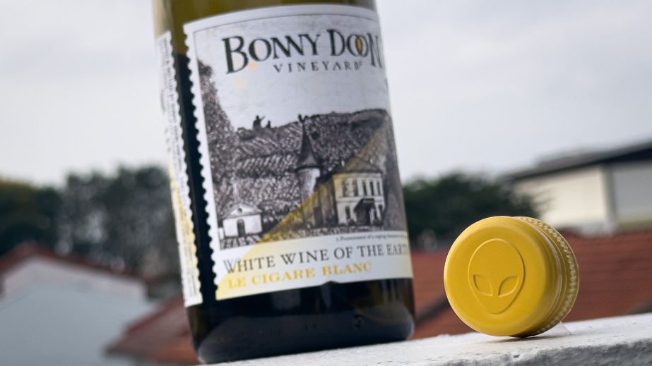 A bottle of Bonny Doon Le Cigare Blanc also showing its screwcap top, featuring an alien face
