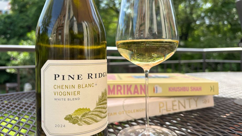 Pine Ridge Chenin Blanc-Viognier bottle and glass of wine outdoors, on table with books