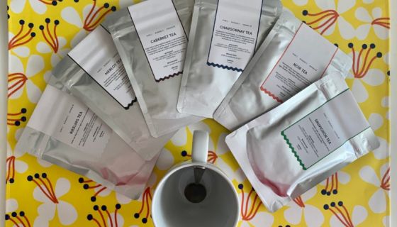 Sachets of wine-themed tea around a mug