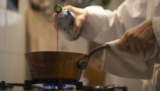 Female chef pouring wine into a pot