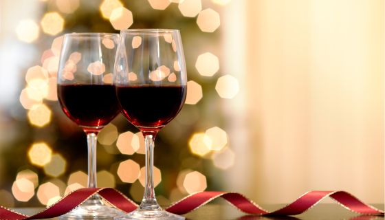 Red wine glasses lit by holiday lights