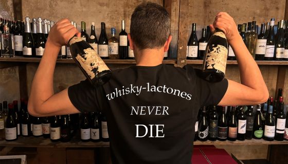 A man wears a tshirt that says 'whisky lactones never die'