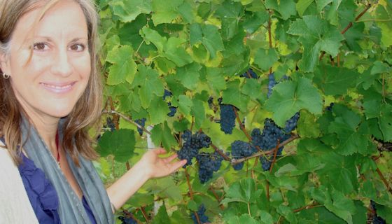 Deborah Hansen in vineyard with dark purple grapes