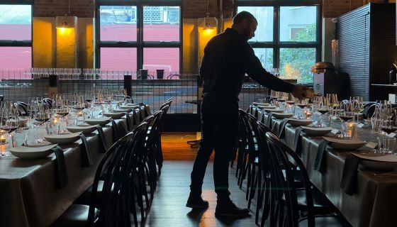 Silhoutted sommelier pouring wine at a long table