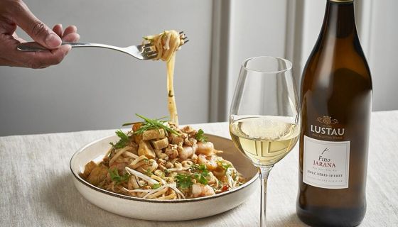 Lustau bottle and glass next to a bowl of pad thai