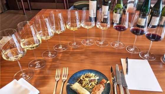 A plate of food surrounded by ten wine glasses