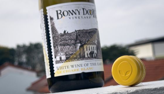 A bottle of Bonny Doon Le Cigare Blanc also showing its screwcap top, featuring an alien face