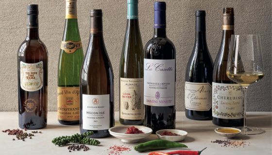 A still life featuring seven bottles of wines and various picquant spices