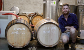 Winemaker Callum Powell kneeling next to his wine barrels