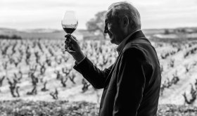 Paco Rodero raising a wine glass in front of a vineyard