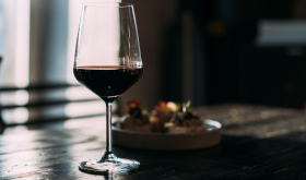 Glass with red wine on the wooden table in the bar; credit Dulin