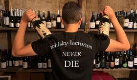 A man wears a tshirt that says 'whisky lactones never die'