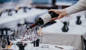 A bottle of Chateau Latour 2010 being poured into a Bordeaux glass
