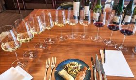 A plate of food surrounded by ten wine glasses