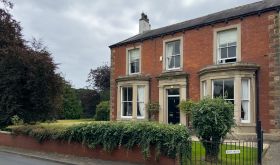 The exterior of Eden House, a red-brick Victorian house in Cumberland