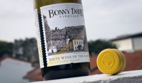 A bottle of Bonny Doon Le Cigare Blanc also showing its screwcap top, featuring an alien face