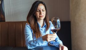 woman inspecting a glass of wine looking disappointed