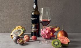 A bottle and glass of sweet Madeira surrounded by tropical fruits