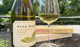 Pine Ridge Chenin Blanc-Viognier bottle and glass of wine outdoors, on table with books