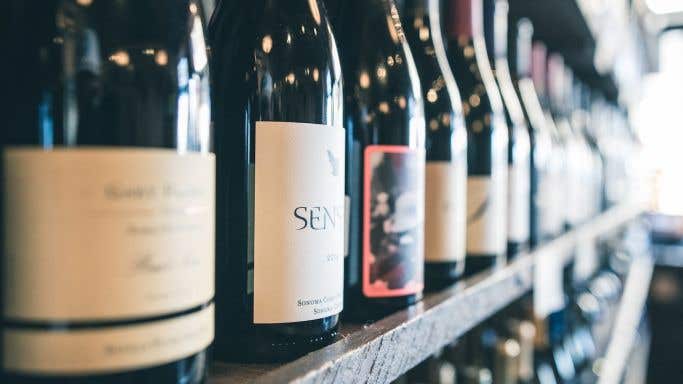 Wine bottles on a shelf by Scott Warman