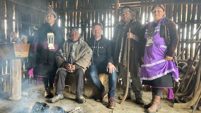 The author, Alistair Cooper MW, sits in a traditional wooden hut with the Mapuche family involved in the making of Tayu wines.