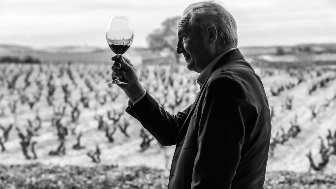 Paco Rodero raising a wine glass in front of a vineyard