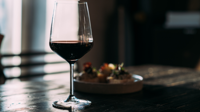 Glass with red wine on the wooden table in the bar; credit Dulin