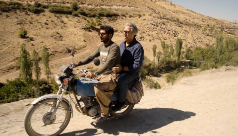 Vahe Keushguerian travelling down a road in Iran on the back of a motorbike
