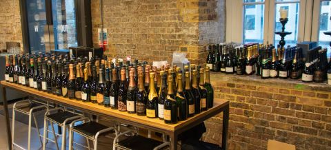 Hundreds of bottles of champagne lined up on a table