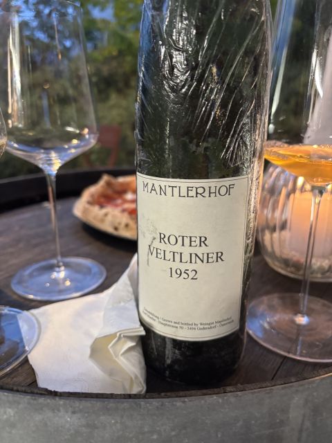 A bottle of Mantlerhof 1952 Roter Veltliner with pizza in the background