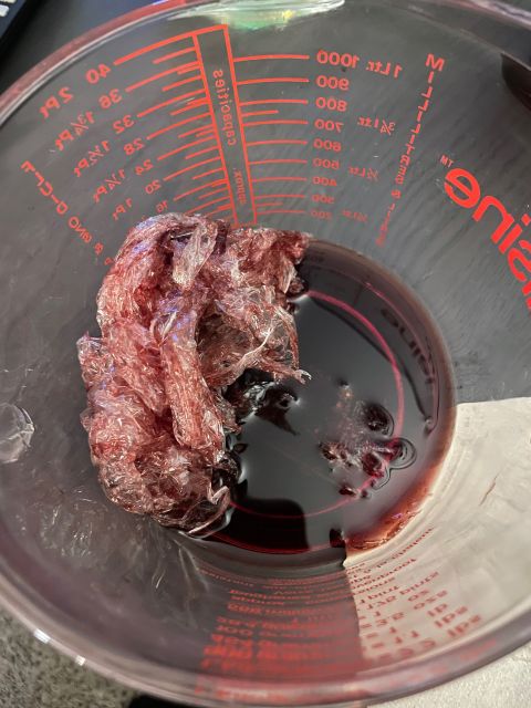 red wine and plastic film in measuring jug