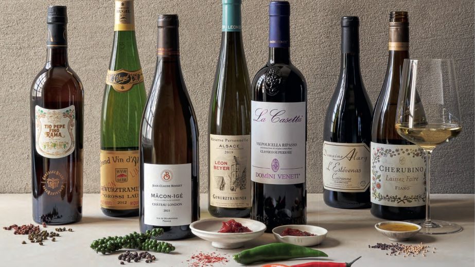 A still life featuring seven bottles of wines and various picquant spices